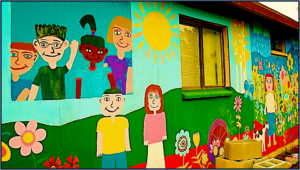 colorful painting on side of a building in a children's style--children, flowers, sunshine