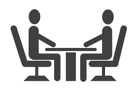 sillouette image of two people sitting at a table and talking