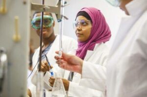 image of scientist wearing hijab surrounded by other scientists of color.